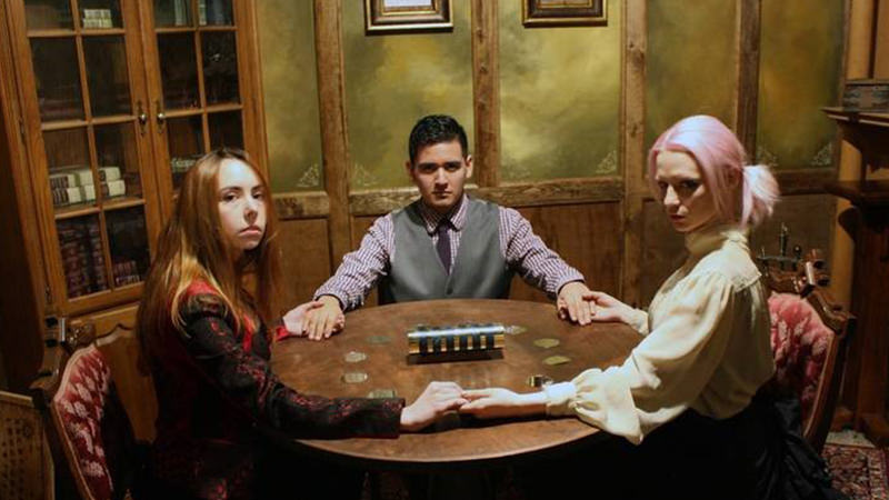 Three people forming a hand circle around the table in an escape room.