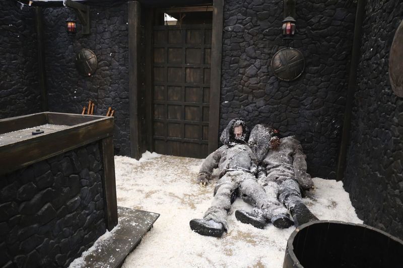 Well-decorated extreme escape room with an imitation of snow and two corpses lying around.